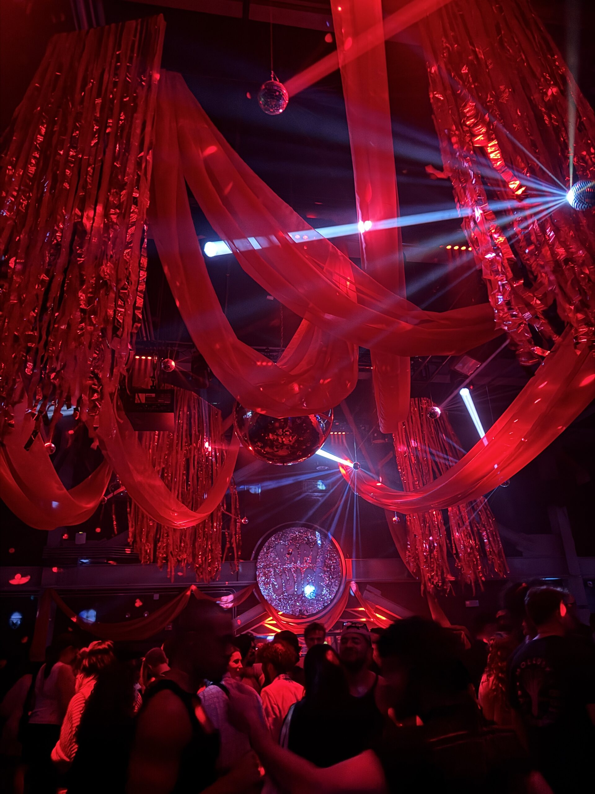 Dancers mingle on the dance floor under streamers and lights at a Papi Juice party