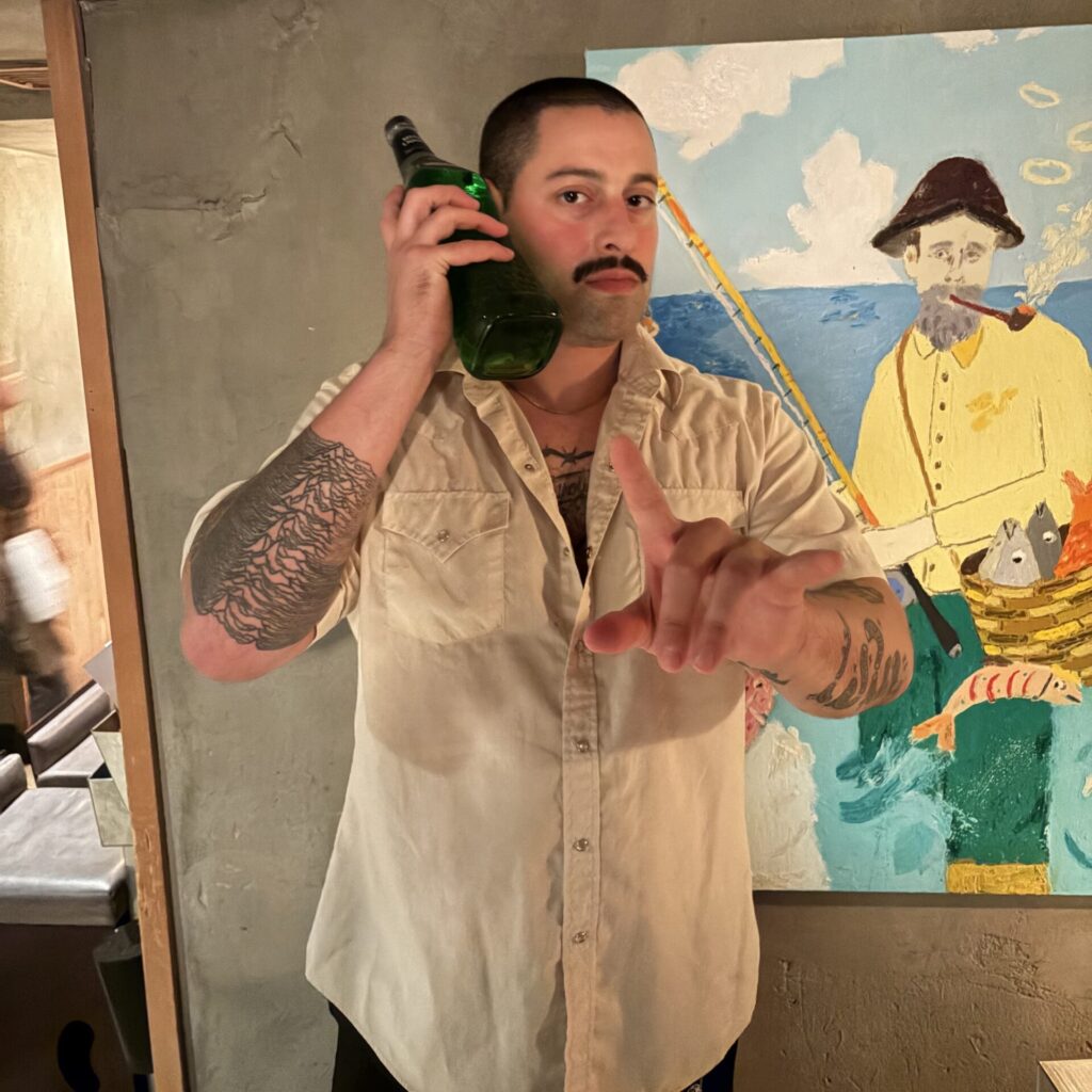 A bartender poses for a portrait with a drink