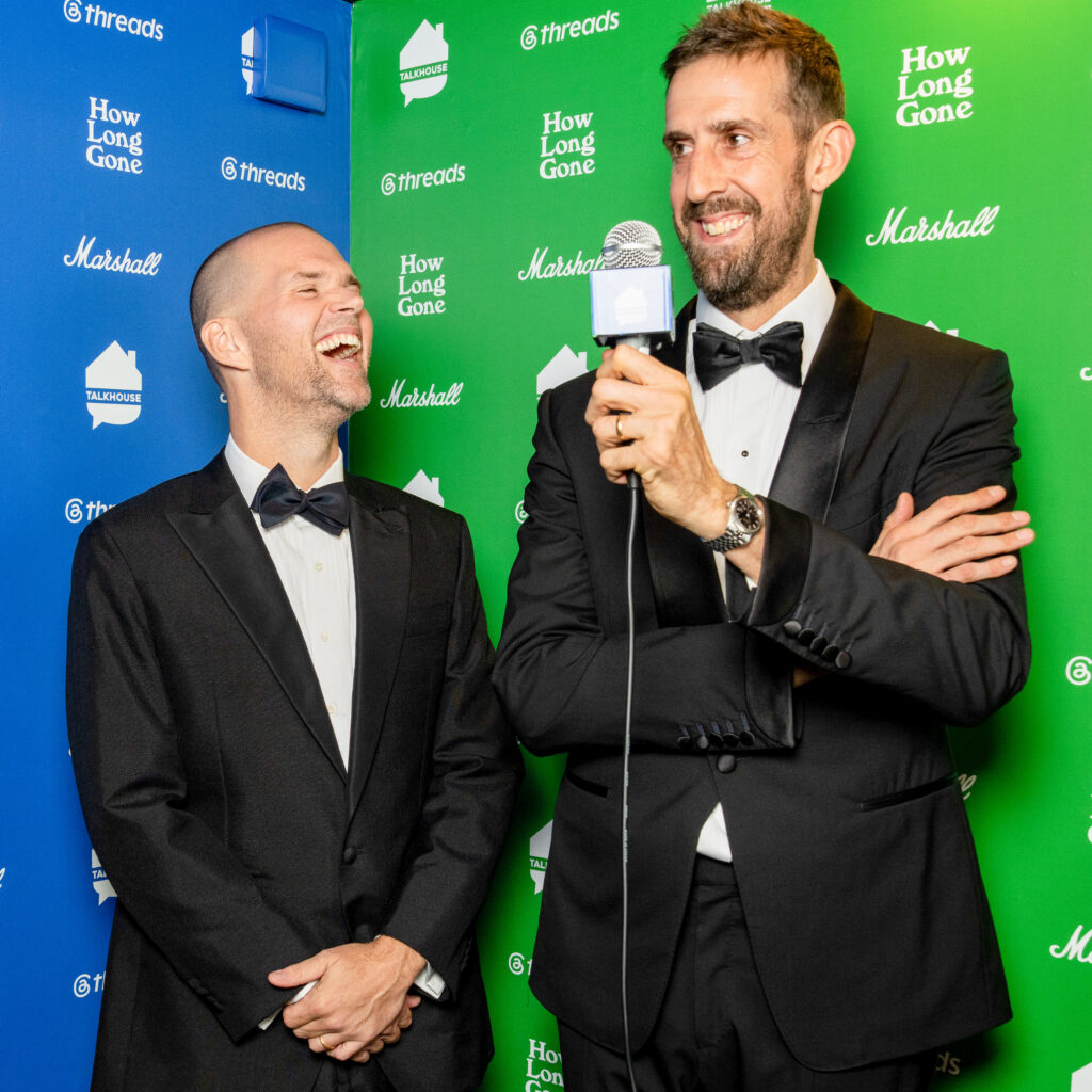 Chris Black and Jason Stewart laugh on the step-and-repeat at the How Long Gone Awards
